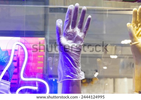Colorful display of gloves and a neon thumbs-up sign in a storefront window