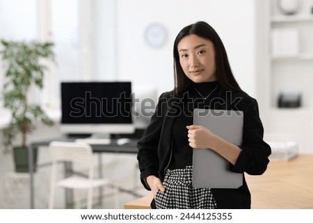 Portrait of beautiful businesswoman with laptop in office. Space for text