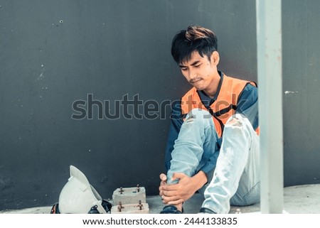 Asian HVAC engineer suffered serious leg injury on the job. Urgent first aid and assistance from coworkers is essential. Expressions of pain on face convey physical and emotional response. Royalty-Free Stock Photo #2444133835