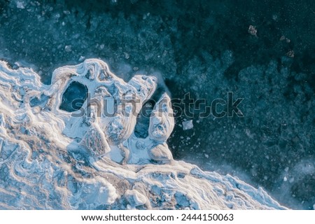 View from above on the icy shore of the freezing sea. Amazing patterns of ice on the coast. Ice floes in sea water. Cold winter weather. Arctic climate. Extreme North. Beautiful natural background. Royalty-Free Stock Photo #2444150063