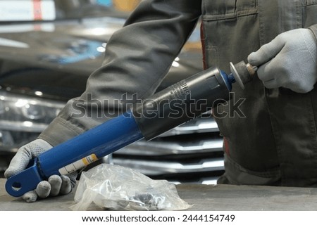 Shock absorber, a car suspension element in the hands of an auto mechanic. A new shock absorber. Close-up. Maintenance control. Royalty-Free Stock Photo #2444154749