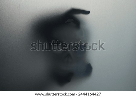 Silhouette of creepy ghost with skull behind cloth