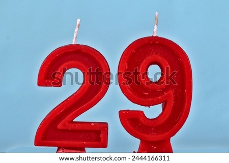 close up on red number twenty ninth birthday candle on a white background.
