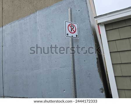 A no parking sign on a pole next to a building.