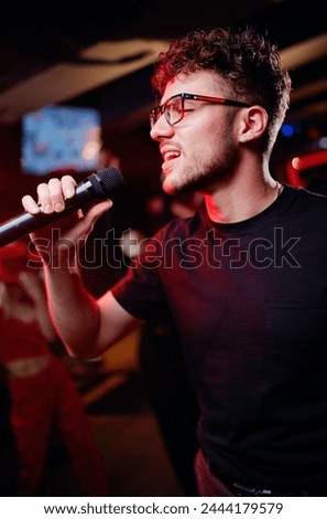 Joy and music. Happy young man is singing in karaoke nightclub
