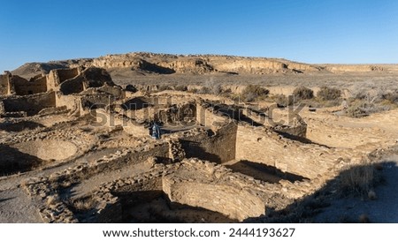 Chaco Culture National Historical Park in New Mexico. Pueblo del Arroyo great house, kivas, and woman in blanket. Chaco Canyon was a major Ancestral Puebloan culture center and has many pueblos.  Royalty-Free Stock Photo #2444193627