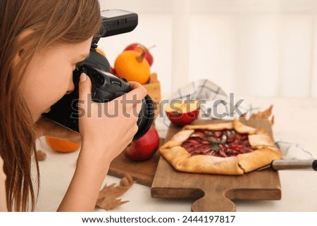 Female photographer taking photo of composition with apple pie in studio