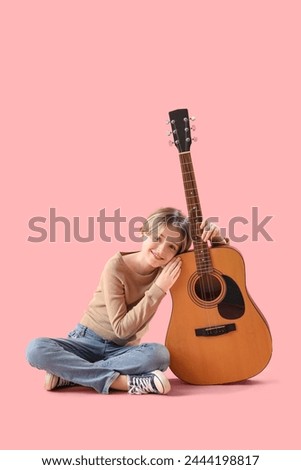 Cute little boy with guitar on pink background