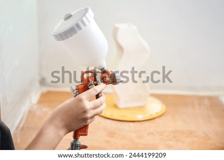 Unrecognizable pottery artisan woman using airbrush to paint ceramic products Royalty-Free Stock Photo #2444199209