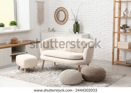 Interior of modern living room with dresser, sofa and poufs Royalty-Free Stock Photo #2444202033