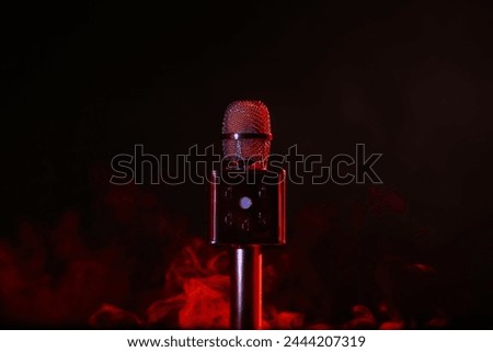 Modern microphone and red smoke on dark background