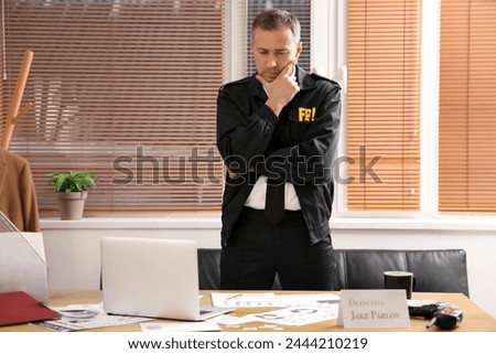 Thoughtful mature FBI agent working at table in office