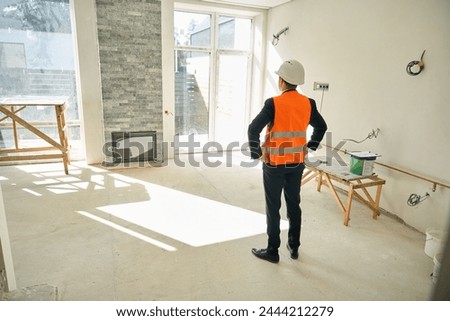 Back view picture of foreman standing in unfinished room