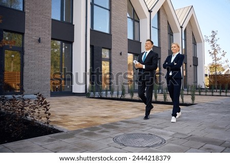 Full length picture of architect and client going near houses