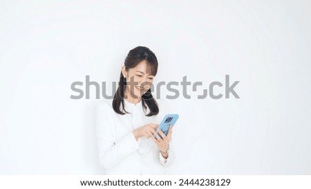 A middle-aged woman looking at her smartphone with a smile.