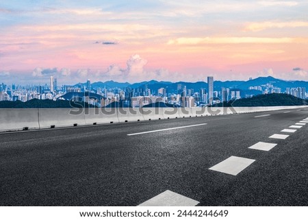 Asphalt highway road and city skyline with modern buildings at dusk