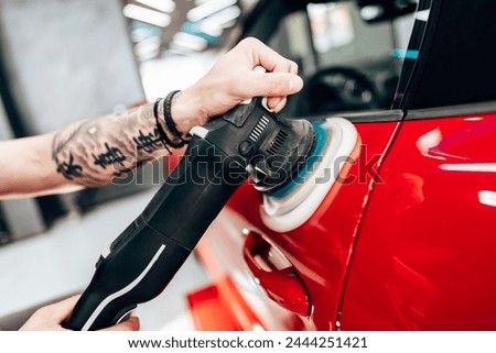 Professional vehicle polishing and detailing service in a modern car workshop. Brightly lit workspace with large led lights. High quality car valeting concept. Royalty-Free Stock Photo #2444251421