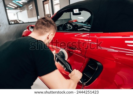 Professional vehicle polishing and detailing service in a modern car workshop. Brightly lit workspace with large led lights. High quality car valeting concept. Royalty-Free Stock Photo #2444251423