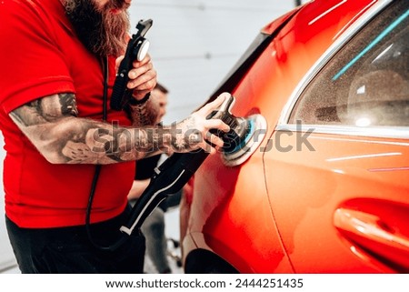 Professional vehicle polishing and detailing service in a modern car workshop. Brightly lit workspace with large led lights. High quality car valeting concept. Royalty-Free Stock Photo #2444251435