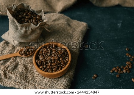 Coffee beans in a wooden plate on a black background.