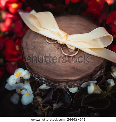 wedding rings on wood surface with flowers