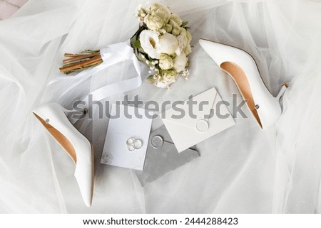 a pair of wedding shoes , a bouquet of flowers , a wedding invitation , and a pair of wedding rings