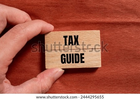 Tax guide words written on wooden blocks with brown background. Conceptual business symbol. Copy space.
