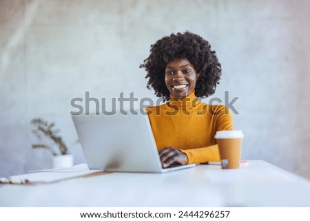 Portrait of smiling African American business woman looking at camera standing in modern office. Successful business and career concept. Successful businesswoman.