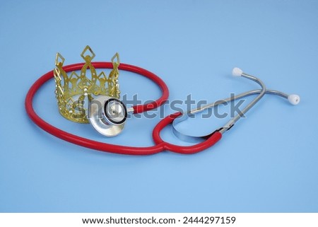 Gold crown with red stethoscope on blue background. Health of royal family concept.	