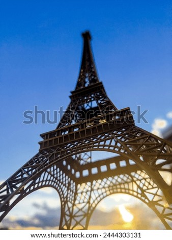 The Eiffel tower is standing with the background of sunset in the evening but the color of the sky is still blue.