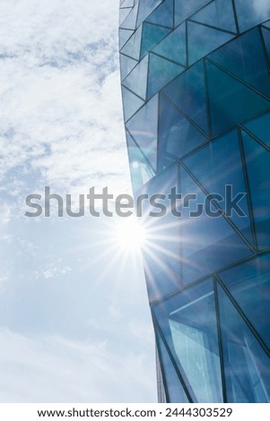 View from below of a glass corporate skyscraper illuminated by sunlight