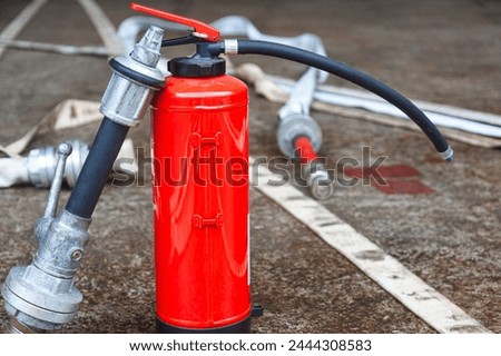 Red fire extinguisher cylinder with unwound fire hoses. Royalty-Free Stock Photo #2444308583