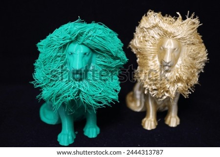 Two models of a lion with a lush mane, printed on a 3D printer, made of plastic, golden and turquoise, on a solid background, photo, close-up.
