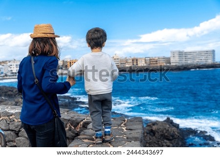 Mother with her son looking at the sea on summer vacation, enjoying family