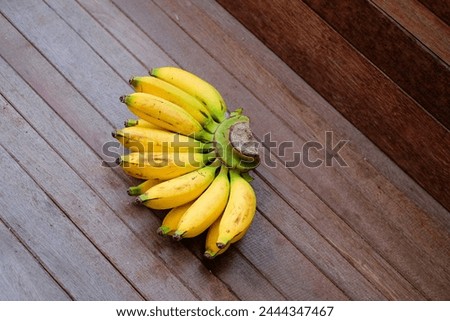 One comb of Pisang Kepok Kuning (musa acuminata) or local yellow banana on a wooden table. bananas that are ripe and ready to be consumed. Indonesian fruit.