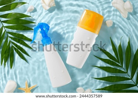 Sun shield: ultimate protection with sunscreen cosmetics.Top view shot of sunscreen, spray bottles nestled among leaves, stones, seashell on water background. The setup provides space for advertising