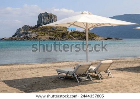 Sunbeds with umbrella on sandy beach of Agios Stefanos. The Greek island of Kos Royalty-Free Stock Photo #2444357805
