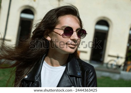 a walk through the city of a girl in black glasses. A smiling girl walks through a modern city. High quality photo