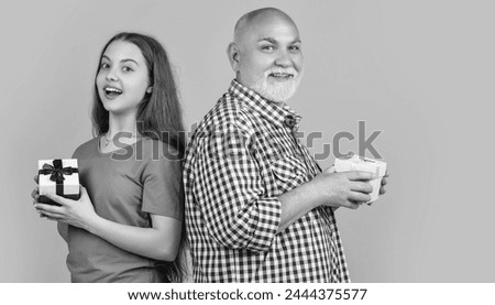 happy amazed teen girl and grandfather with present box for anniversary