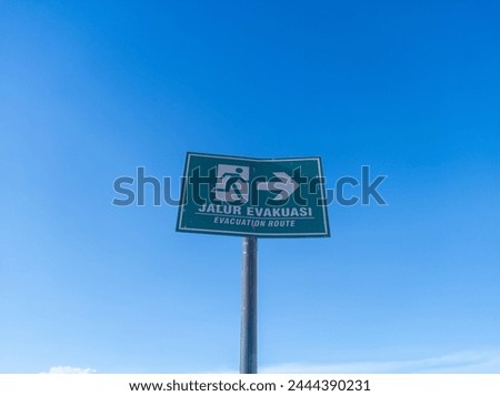 warning board with jalur evakuasi writing in English evacuation route on a clear blue sky background
