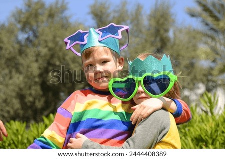 Brothers hug, boys celebrate birthday. Best friends, schoolchildren. Children in masquerade glasses and crowns - a fun holiday