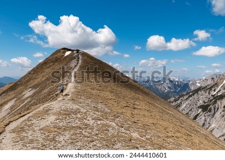Hiker woman on idyllic hiking trail on alpine meadow with scenic view of majestic Hochschwab mountain range, Styria, Austria. Wanderlust in remote Austrian Alps. Sense of escapism, peace, reflection Royalty-Free Stock Photo #2444410601