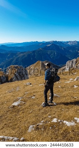Hiker man on idyllic hiking trail on alpine meadow with scenic view of majestic Hochschwab mountain range, Styria, Austria. Wanderlust in remote Austrian Alps. Sense of escapism, peace, reflection Royalty-Free Stock Photo #2444410633