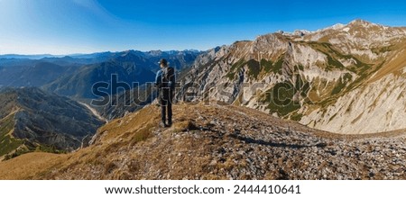 Hiker man on idyllic hiking trail on alpine meadow with scenic view of majestic Hochschwab mountain range, Styria, Austria. Wanderlust in remote Austrian Alps. Sense of escapism, peace, reflection Royalty-Free Stock Photo #2444410641