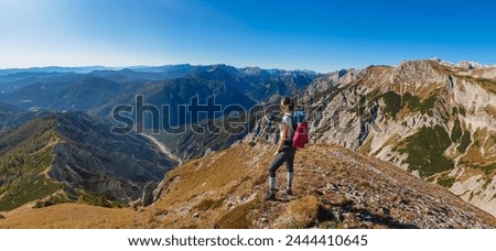 Hiker woman on idyllic hiking trail on alpine meadow with scenic view of majestic Hochschwab mountain range, Styria, Austria. Wanderlust in remote Austrian Alps. Sense of escapism, peace, reflection Royalty-Free Stock Photo #2444410645