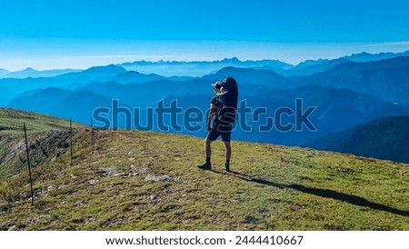Man with baby carrier looking at magical mountain peaks of Karawanks and Julian Alps seen from Goldeck, Latschur group, Gailtal Alps, Carintha, Austria. Mystical atmosphere in Austrian Alps in summer Royalty-Free Stock Photo #2444410667