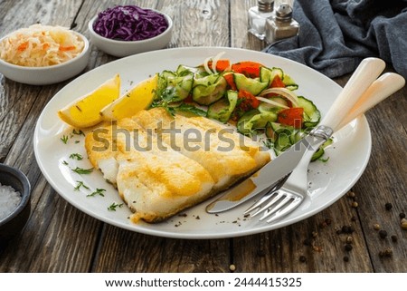 Seared halibut fillet and fresh vegetables on wooden table 