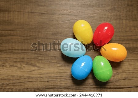 six colorful plastic Easter eggs in red, yellow, orange, green, blue, and light blue photographed from above in a spiral with copy space and copy text available