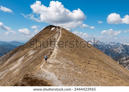 Hiker woman on idyllic hiking trail on alpine meadow with scenic view of majestic Hochschwab mountain range, Styria, Austria. Wanderlust in remote Austrian Alps. Sense of escapism, peace, reflection Royalty-Free Stock Photo #2444423965