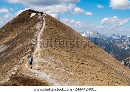 Hiker woman on idyllic hiking trail on alpine meadow with scenic view of majestic Hochschwab mountain range, Styria, Austria. Wanderlust in remote Austrian Alps. Sense of escapism, peace, reflection Royalty-Free Stock Photo #2444424005